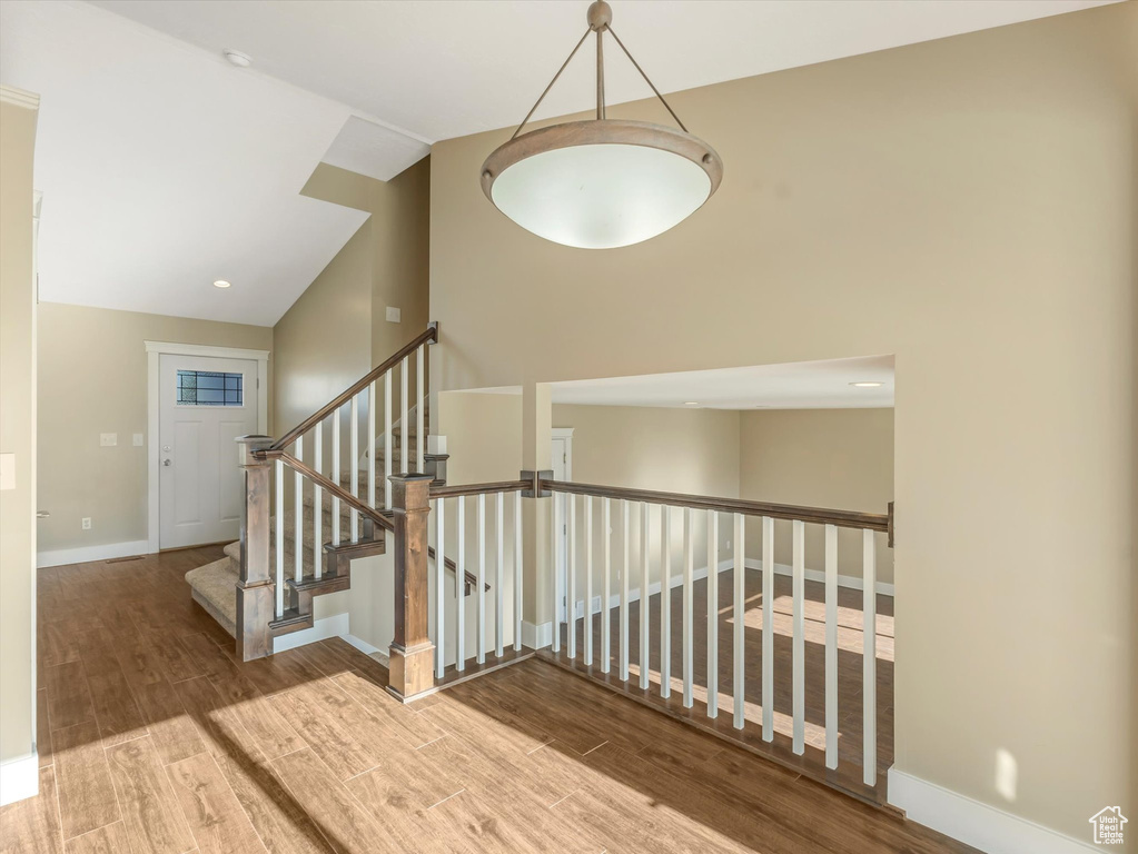 Stairs featuring wood finished floors, vaulted ceiling, and baseboards