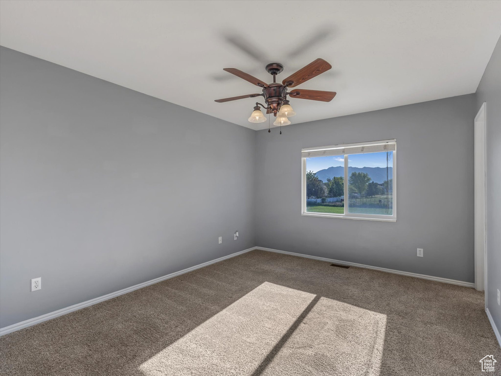 Empty room featuring carpet, a ceiling fan, and baseboards
