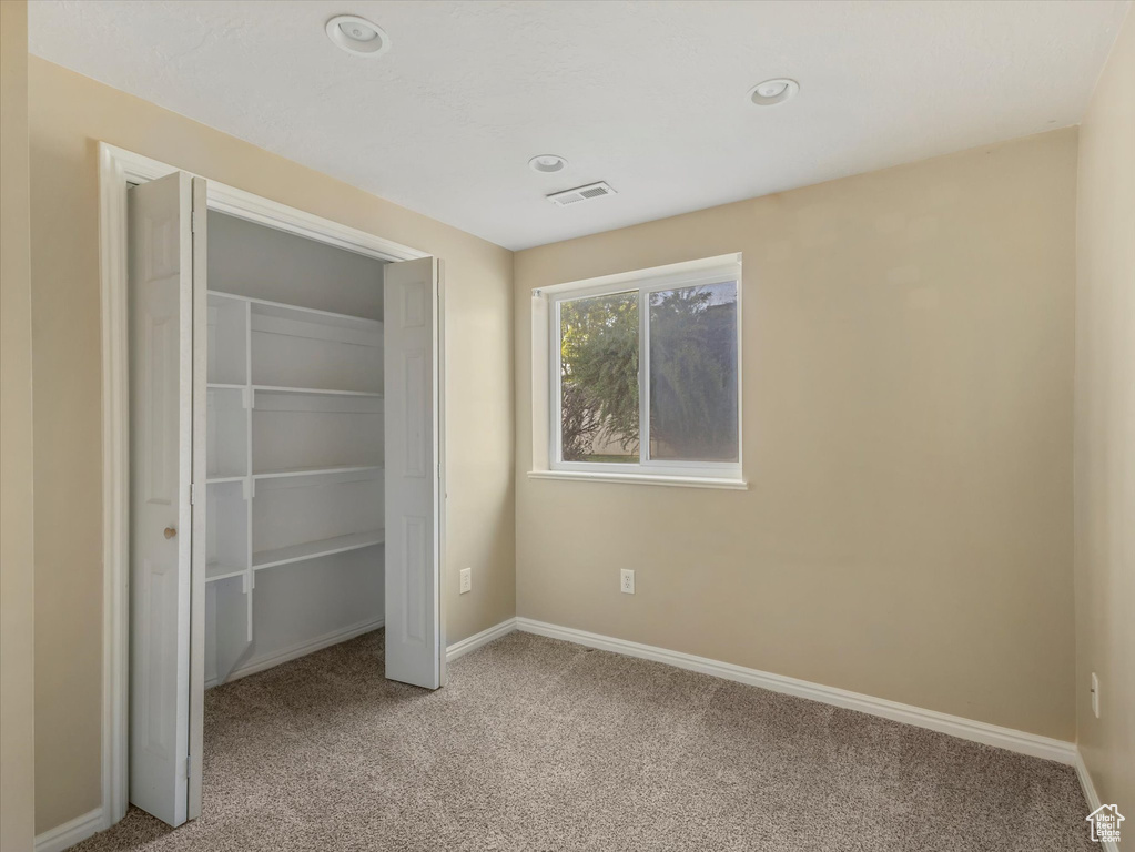 Unfurnished bedroom featuring light colored carpet, a closet, recessed lighting, and baseboards