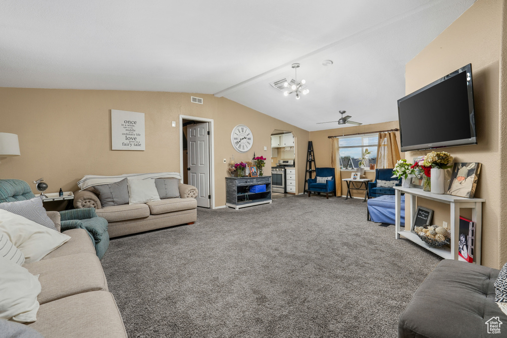 Living room featuring carpet, a ceiling fan, vaulted ceiling, and a chandelier