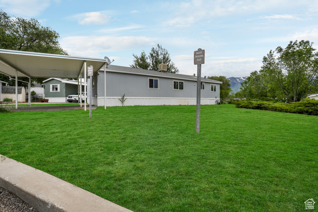 View of side of property featuring a carport, a lawn, and a mountain view