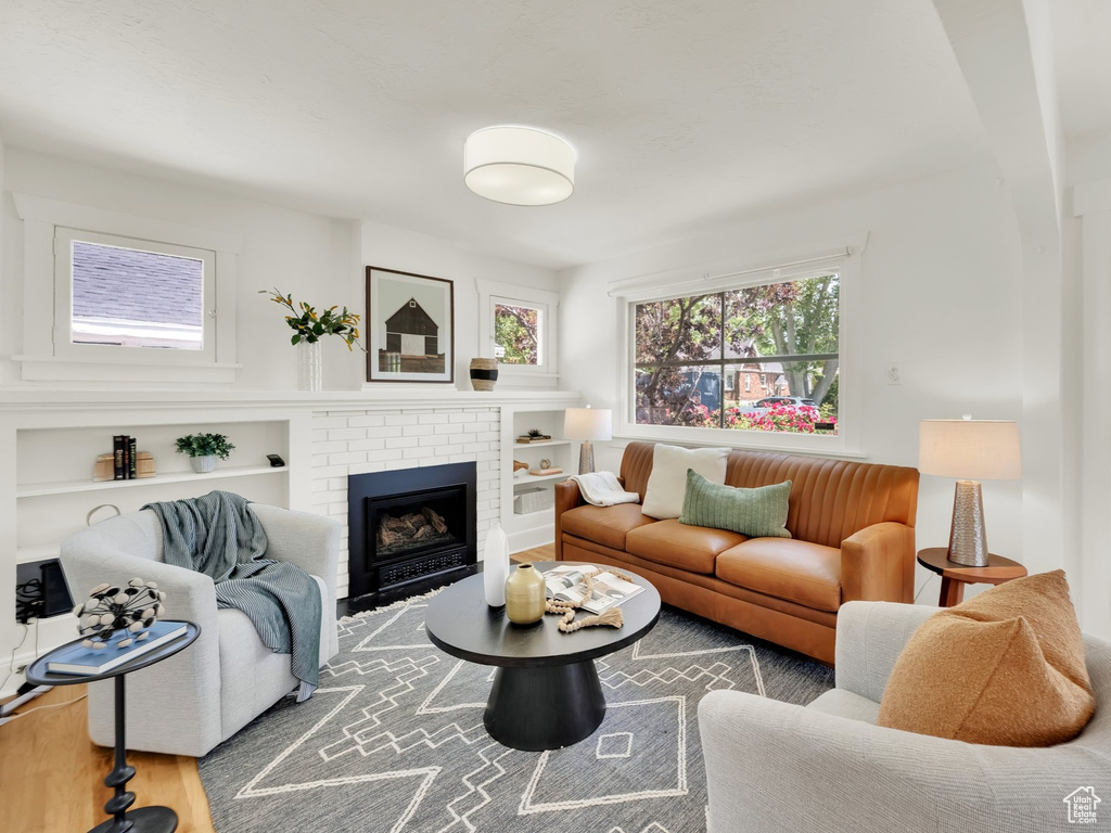Living area with wood finished floors, a brick fireplace, and built in shelves