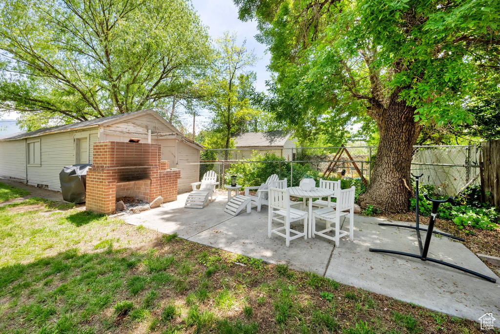 Fenced backyard featuring a patio, an outdoor structure, and area for grilling