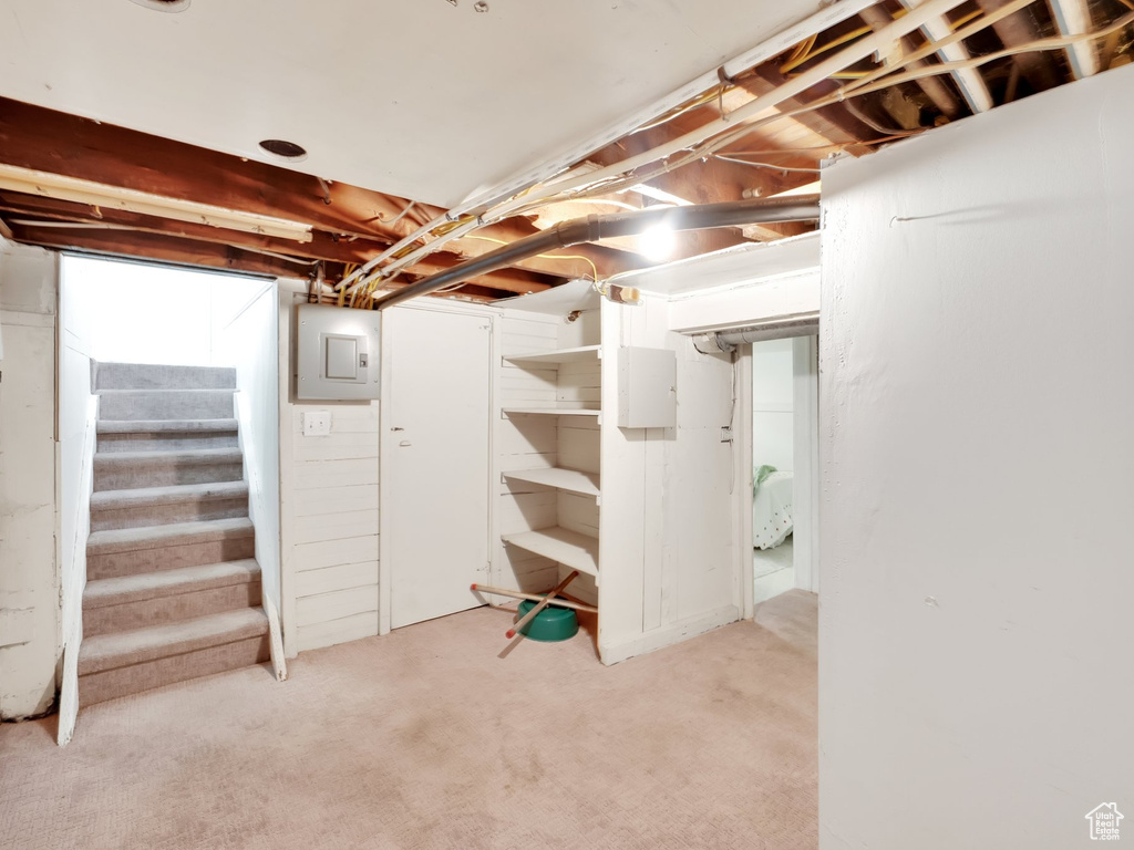 Basement featuring stairway, light carpet, and electric panel