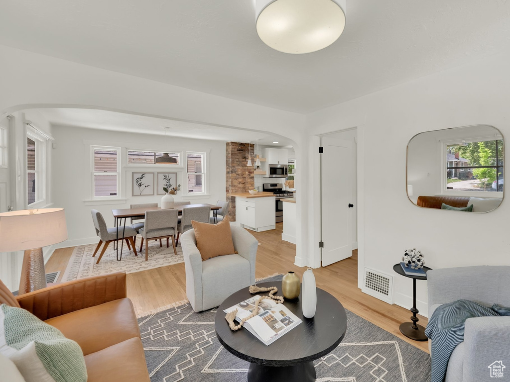 Living room featuring arched walkways, wood finished floors, and plenty of natural light