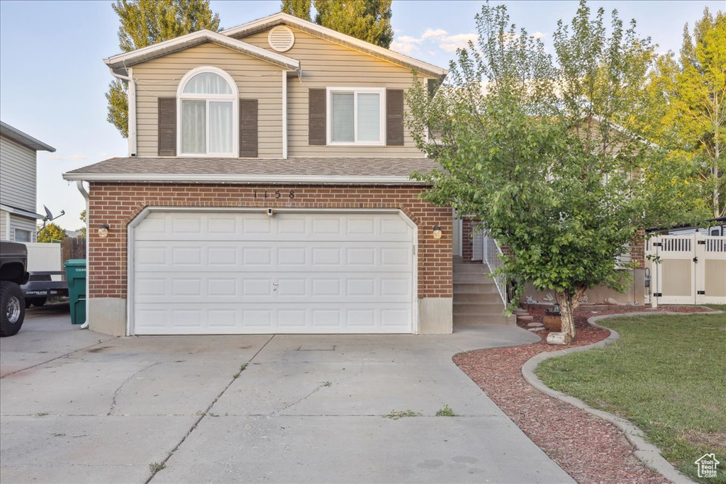 View of front of home with brick siding, a garage, concrete driveway, and a shingled roof