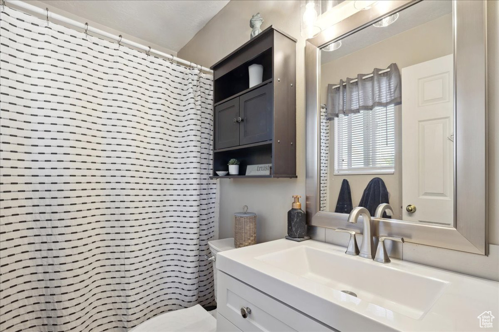 Bathroom with vanity, toilet, and a shower with shower curtain