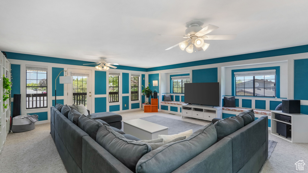 Living area featuring light colored carpet, ceiling fan, and plenty of natural light