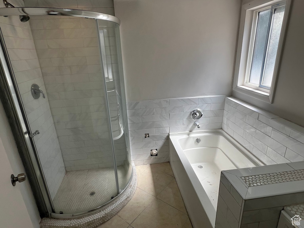 Bathroom with tile walls, a stall shower, a garden tub, tile patterned flooring, and wainscoting
