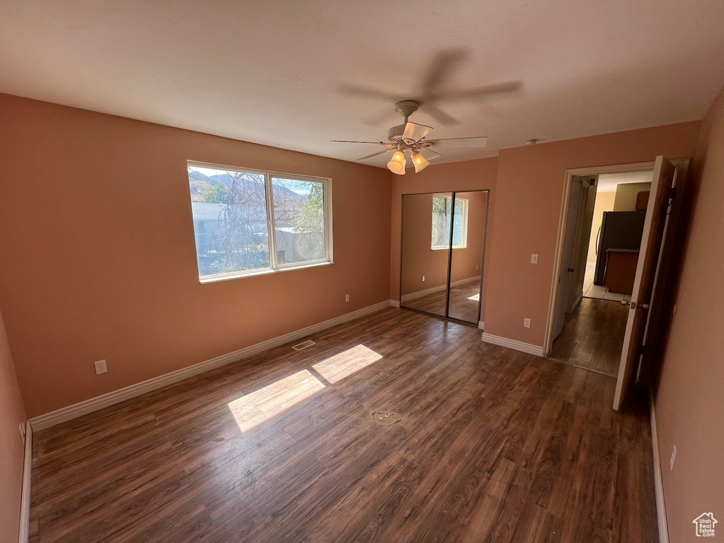 Unfurnished bedroom with dark wood-style flooring, baseboards, a closet, and ceiling fan