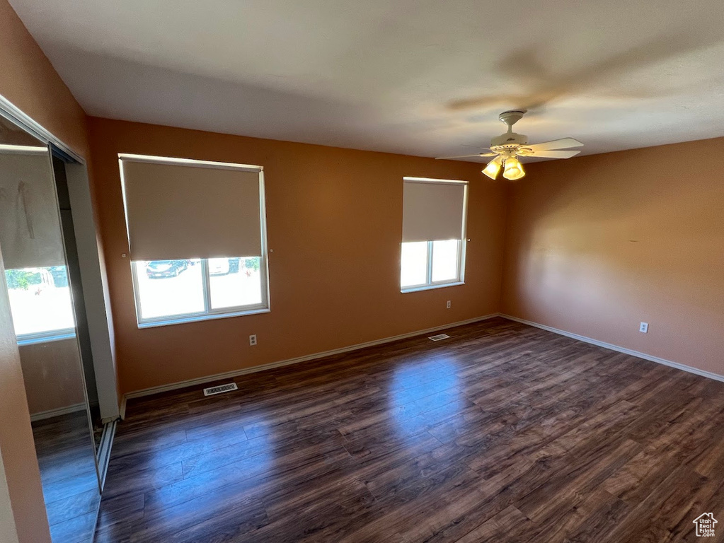 Unfurnished room with ceiling fan, dark wood-style floors, and baseboards