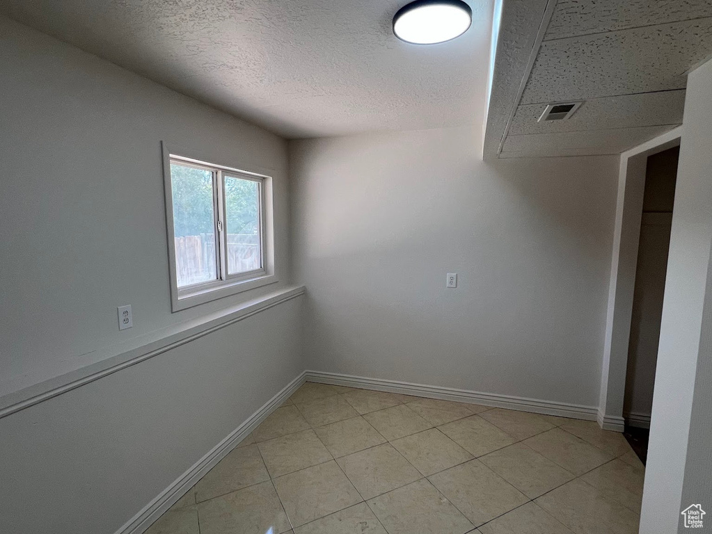 Spare room featuring baseboards, a textured ceiling, and light tile patterned floors