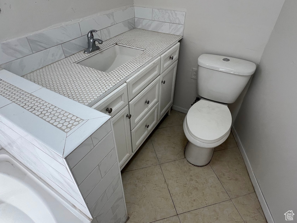 Half bath featuring toilet, vanity, and tile patterned floors