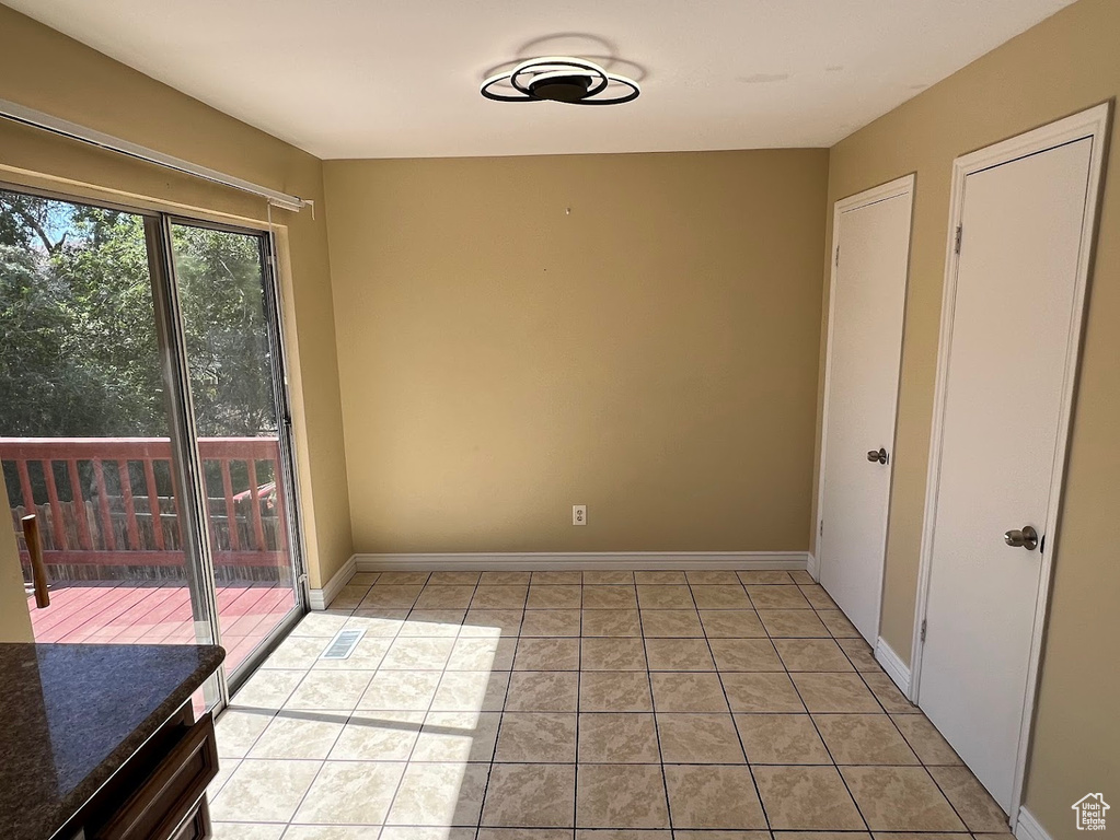 Unfurnished dining area with light tile patterned flooring and baseboards