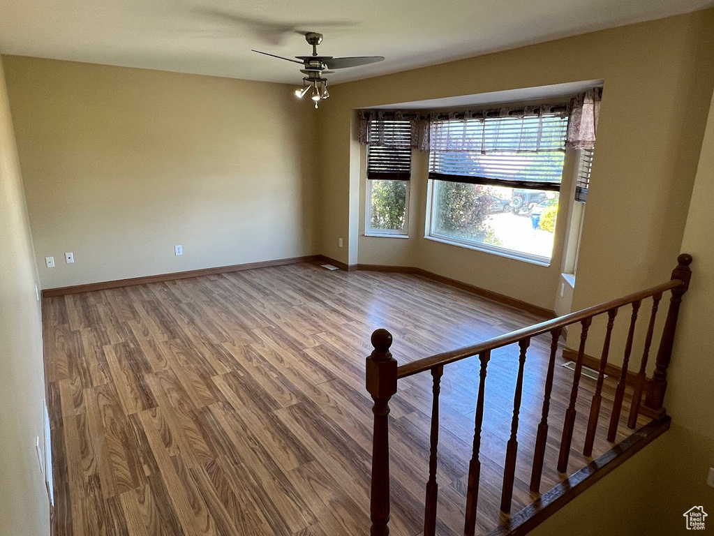 Spare room featuring wood finished floors, a ceiling fan, and baseboards