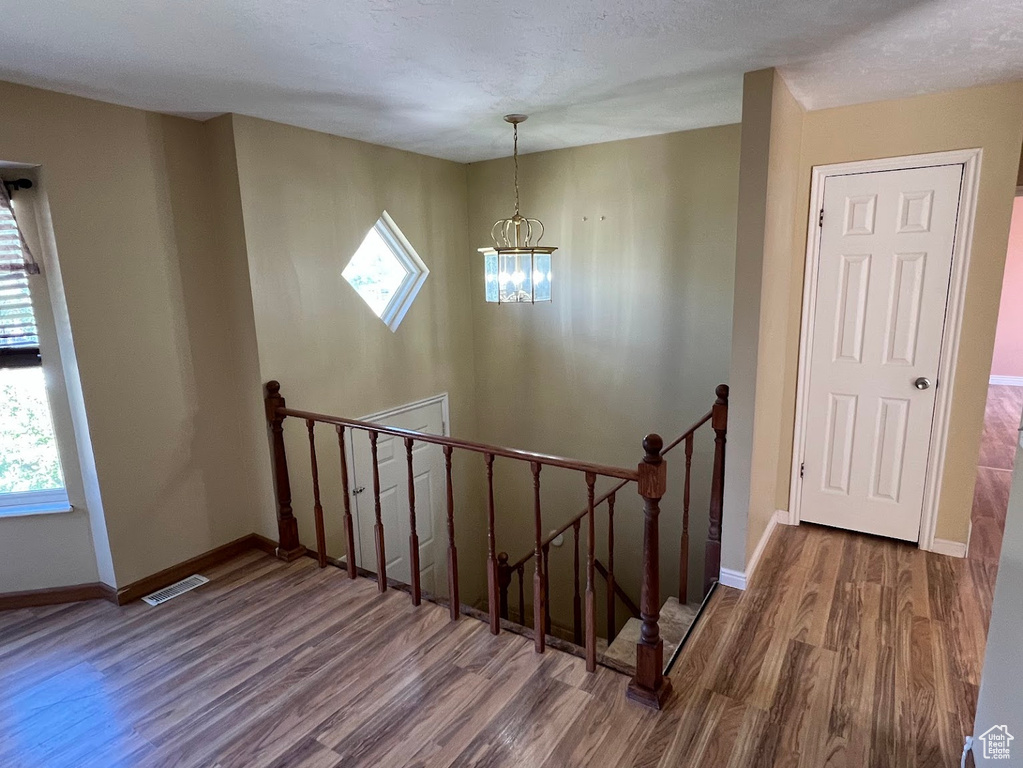 Stairway with wood finished floors, a chandelier, and baseboards
