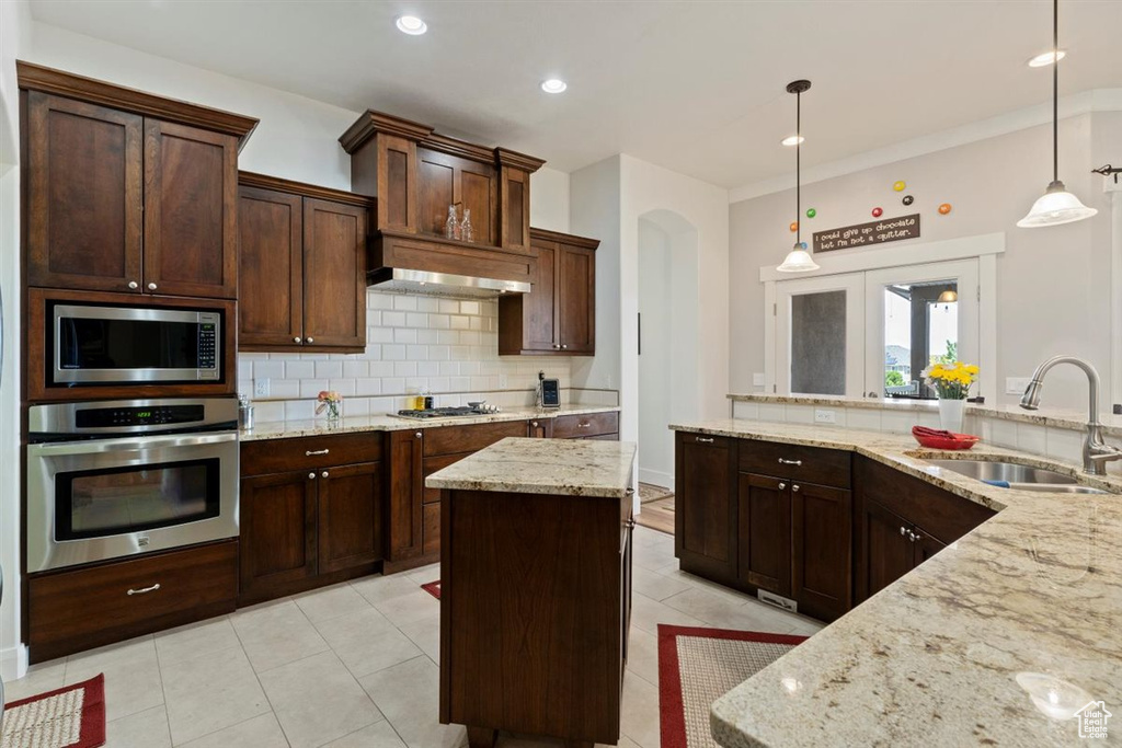 Kitchen with appliances with stainless steel finishes, a sink, decorative backsplash, decorative light fixtures, and recessed lighting