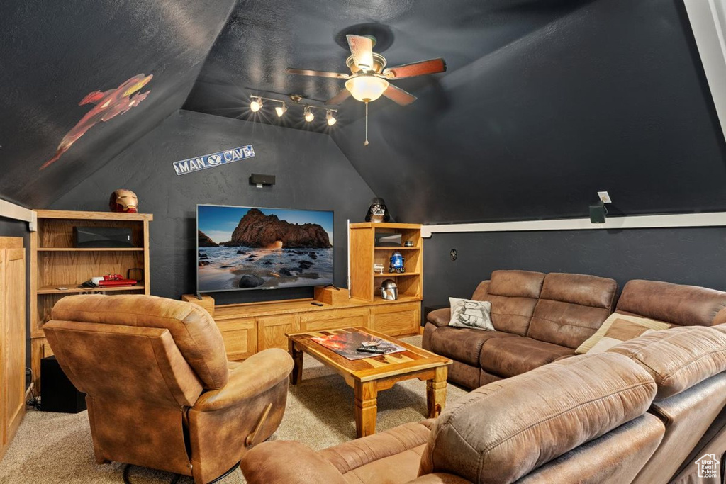Home theater room with vaulted ceiling, a ceiling fan, and carpet flooring