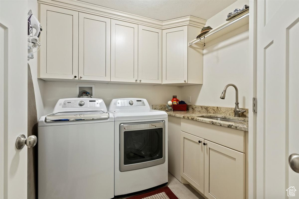 Laundry room featuring separate washer and dryer, cabinet space, and light tile patterned floors