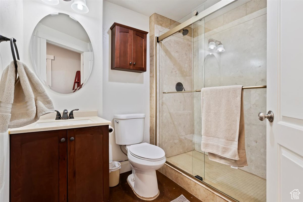 Bathroom with toilet, vanity, and a stall shower