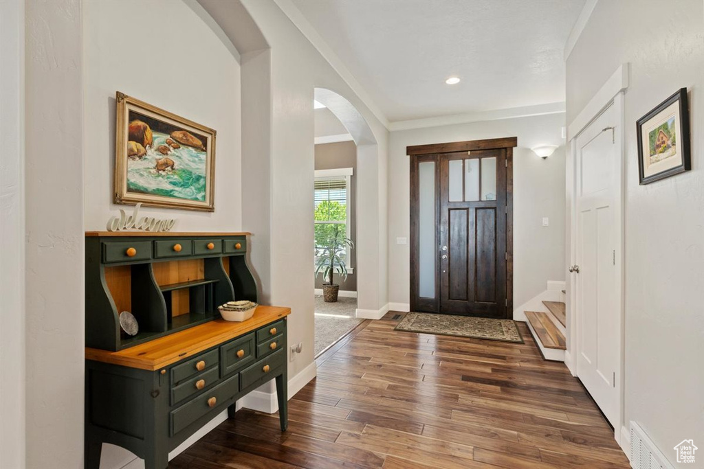 Foyer with arched walkways, dark wood-style flooring, baseboards, and recessed lighting