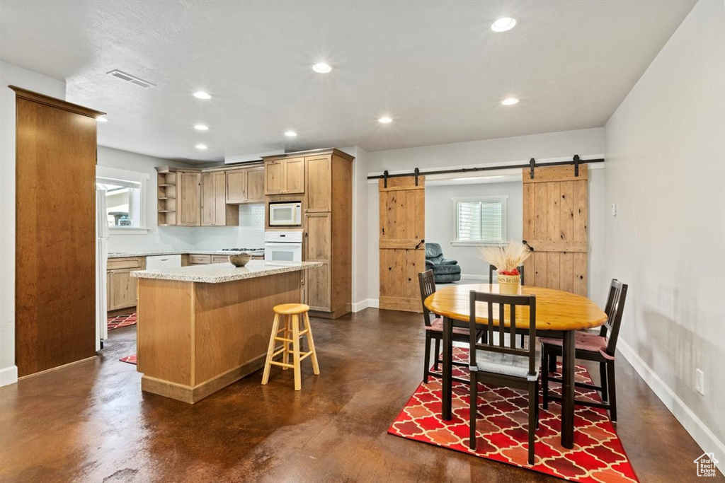 Kitchen featuring white appliances, a barn door, concrete flooring, open shelves, and baseboards
