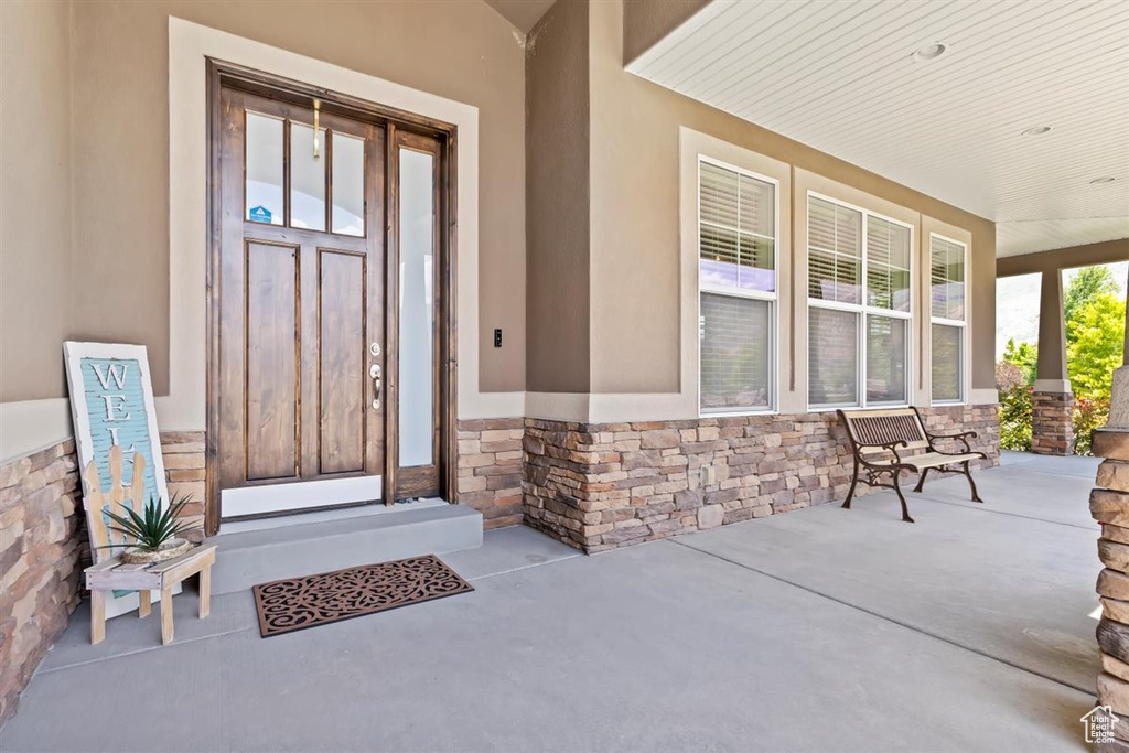 View of exterior entry with a porch, stone siding, and stucco siding