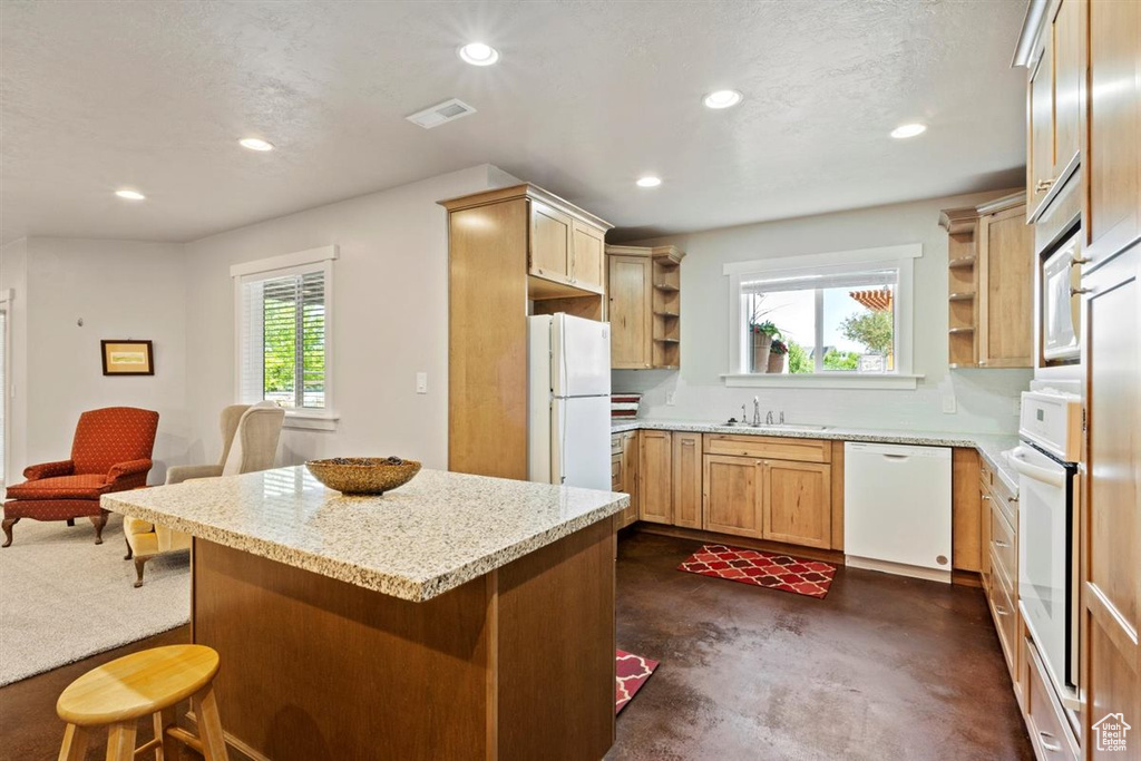 Kitchen featuring open shelves, white appliances, a sink, recessed lighting, and a breakfast bar