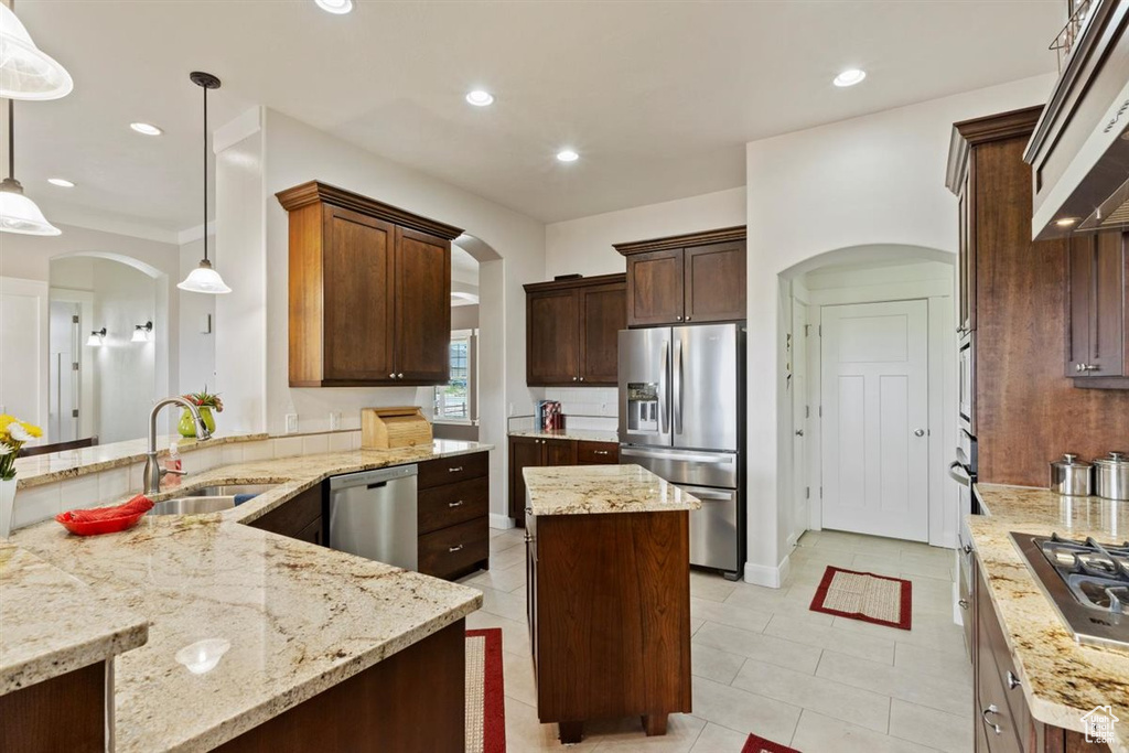 Kitchen with appliances with stainless steel finishes, arched walkways, a sink, light stone counters, and recessed lighting