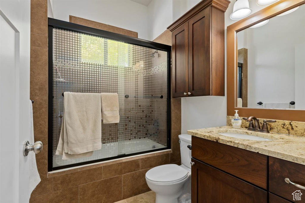 Bathroom with toilet, vanity, and tiled shower / bath combo