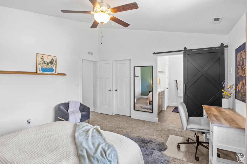 Carpeted bedroom with a barn door, a ceiling fan, high vaulted ceiling, and a desk