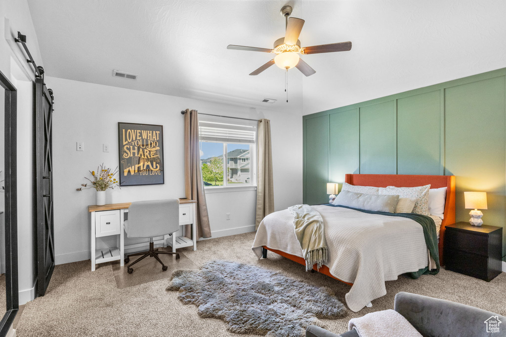 Carpeted bedroom featuring a barn door, baseboards, and a ceiling fan