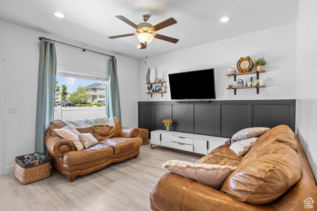 Living area featuring ceiling fan, wood finished floors, wainscoting, recessed lighting, and a decorative wall