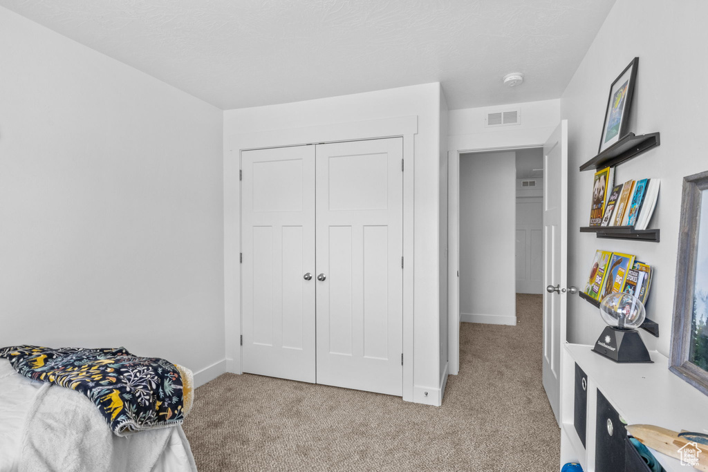 Bedroom with light colored carpet, baseboards, and a closet