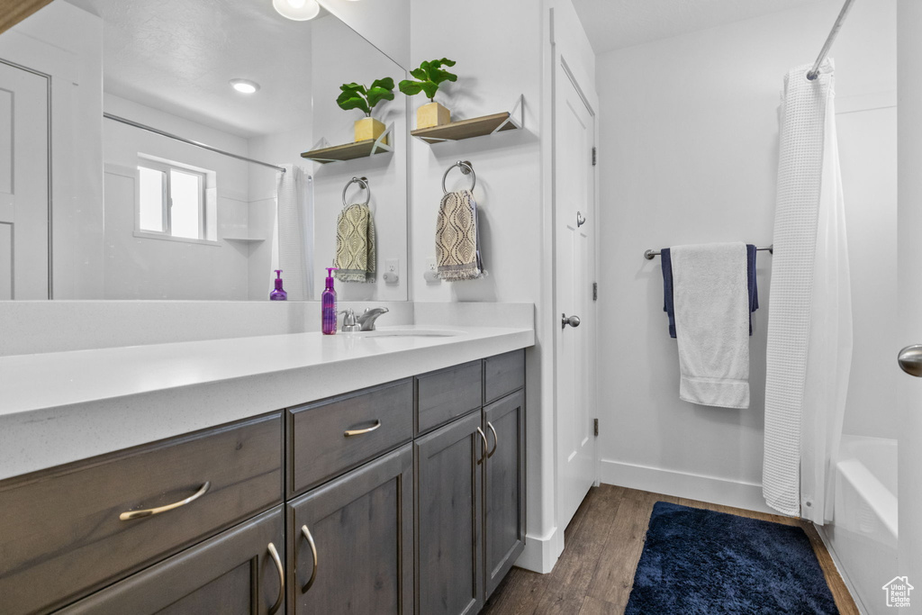 Bathroom with vanity, baseboards, shower / bath combination with curtain, and wood finished floors