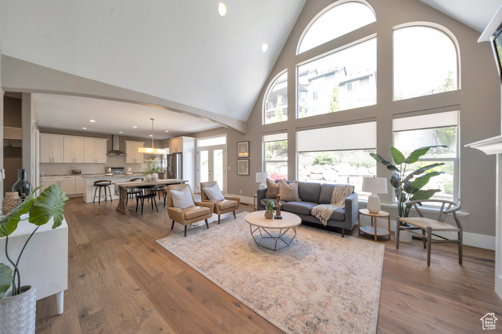 Living room with high vaulted ceiling, arched walkways, hardwood / wood-style floors, recessed lighting, and baseboards