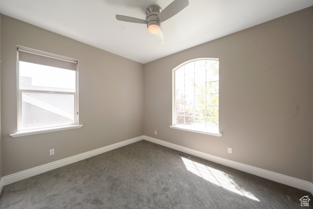 Spare room featuring carpet floors, a ceiling fan, and baseboards
