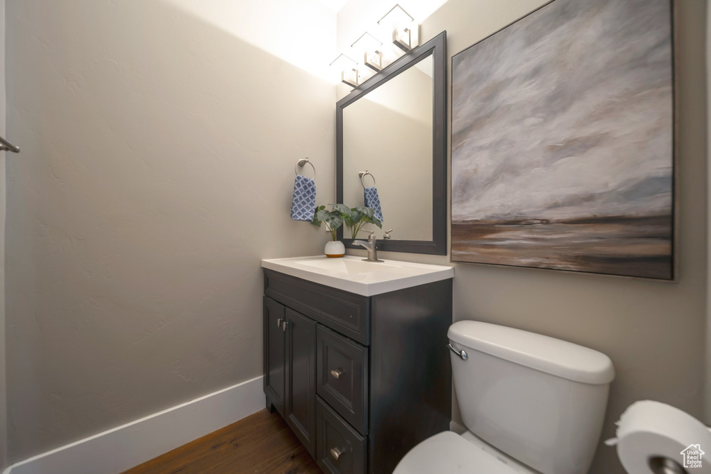 Bathroom featuring toilet, vanity, and wood finished floors