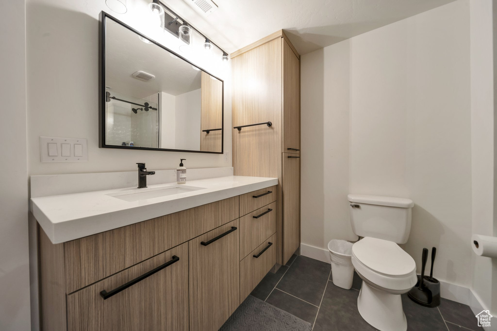 Full bathroom with toilet, vanity, tile patterned floors, and baseboards