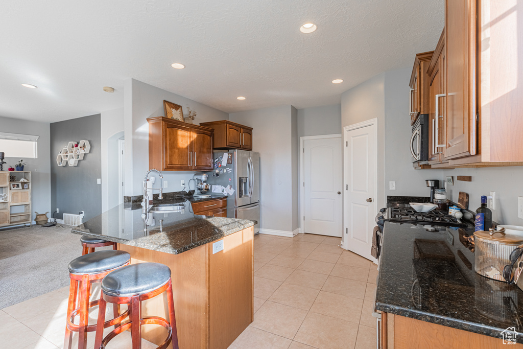 Kitchen featuring stainless steel appliances, a sink, a peninsula, a kitchen breakfast bar, and brown cabinets