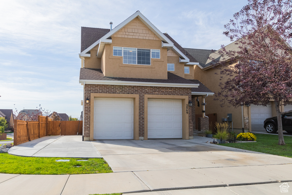 View of front of home featuring an attached garage, stucco siding, concrete driveway, and roof with shingles