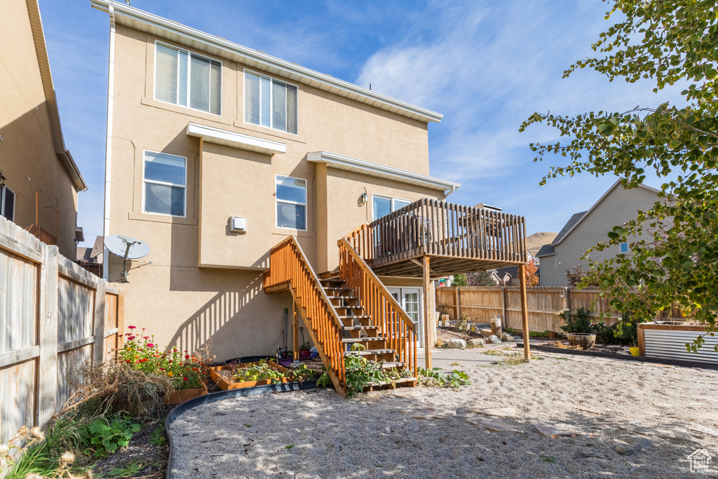 Rear view of house featuring a fenced backyard, a deck, stairway, and stucco siding