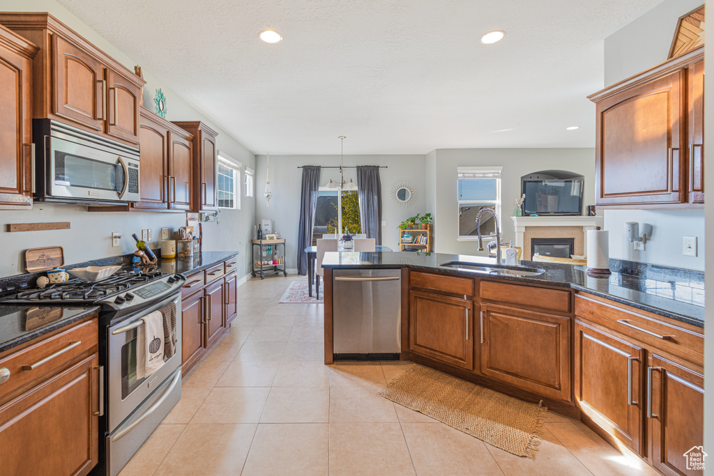 Kitchen featuring appliances with stainless steel finishes, a sink, recessed lighting, a peninsula, and dark stone countertops