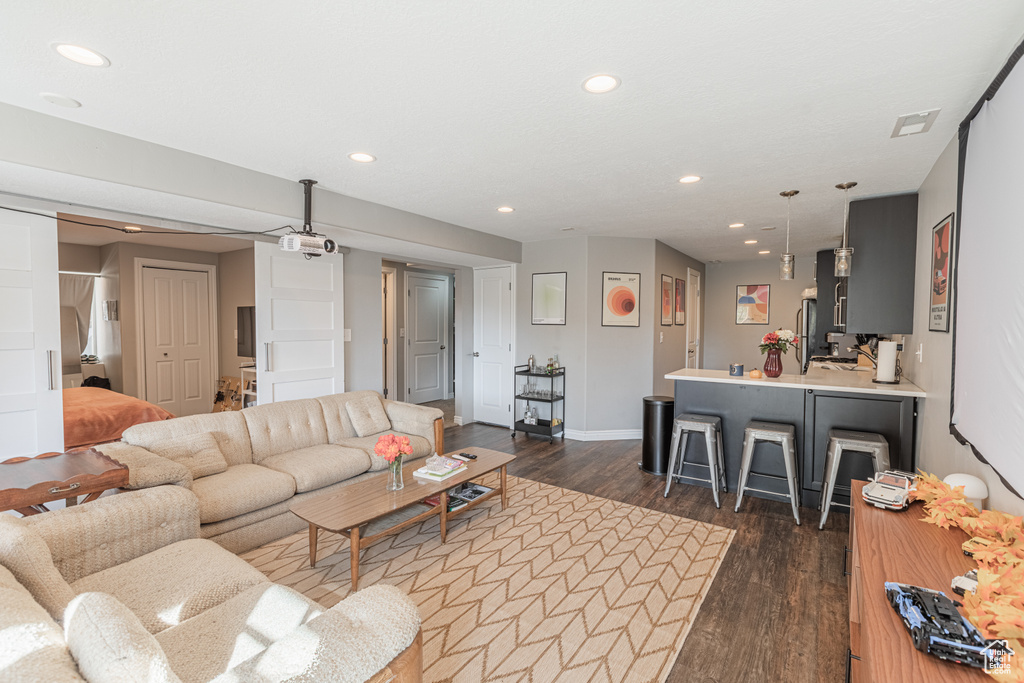 Living room featuring dark wood-style flooring, recessed lighting, and baseboards