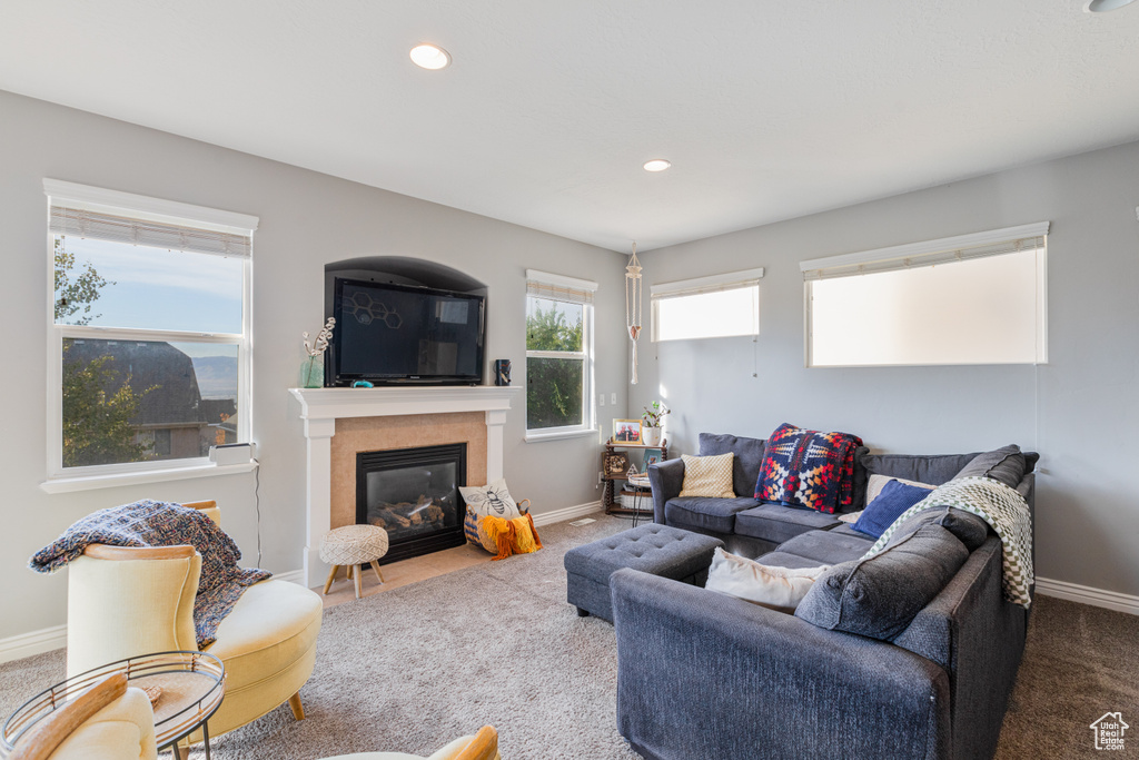 Living room featuring carpet floors, baseboards, a fireplace with flush hearth, and recessed lighting