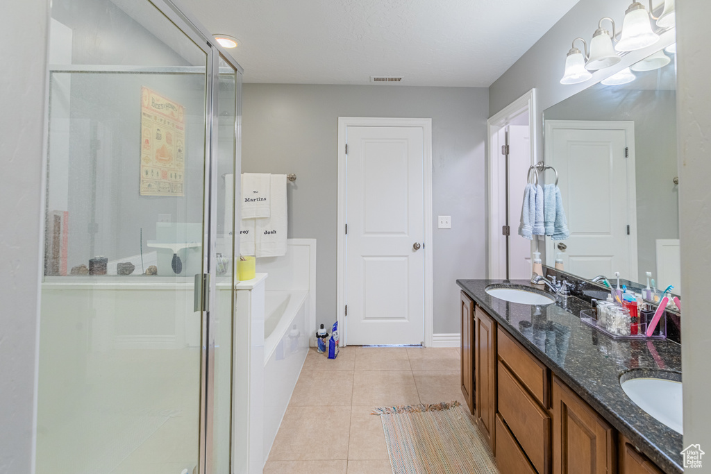 Full bathroom featuring a shower stall, double vanity, a garden tub, tile patterned floors, and baseboards