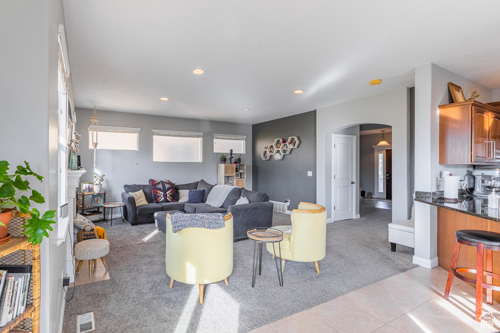 Living area featuring arched walkways, light carpet, light tile patterned floors, recessed lighting, and bar
