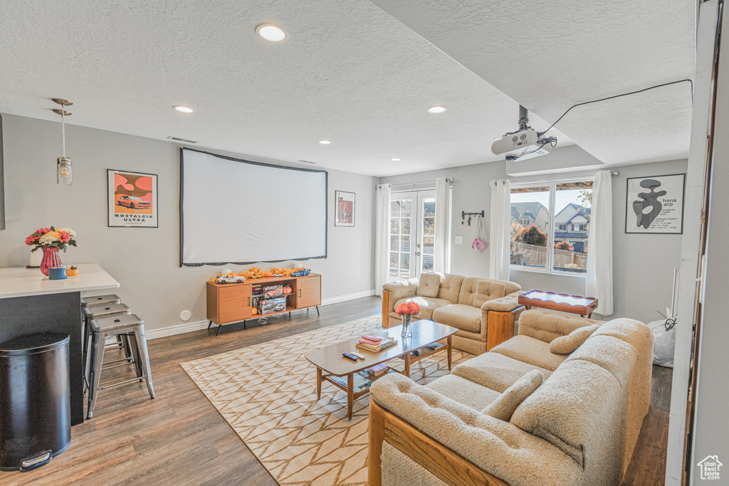 Home theater with a textured ceiling, wood finished floors, recessed lighting, and baseboards