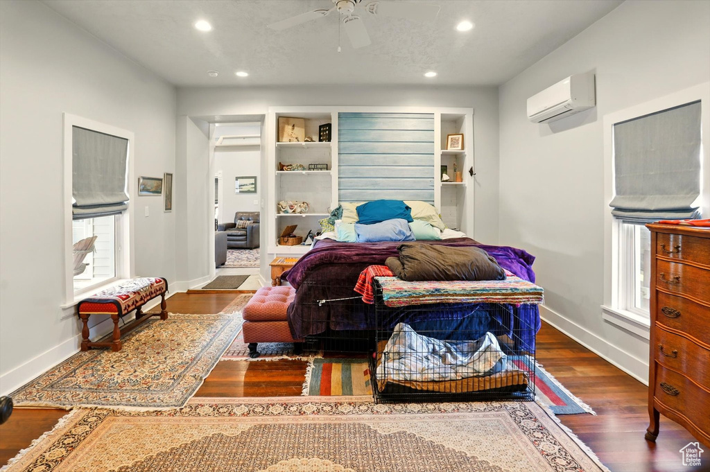 Bedroom with recessed lighting, wood finished floors, a wall unit AC, baseboards, and multiple windows