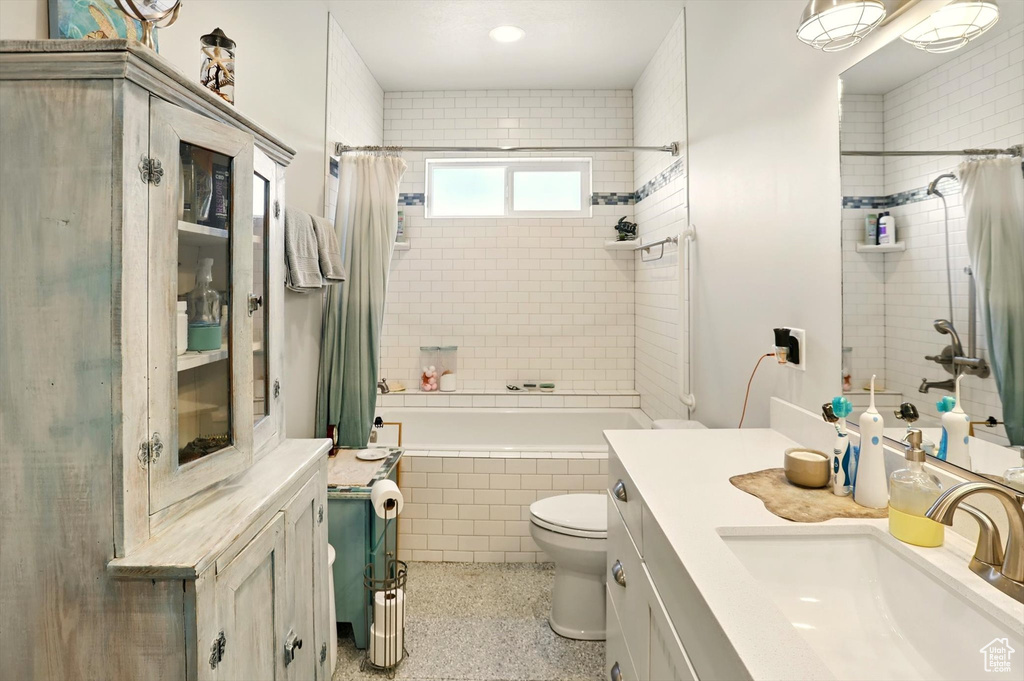 Full bathroom featuring tiled shower / bath, vanity, toilet, and speckle patterned floor
